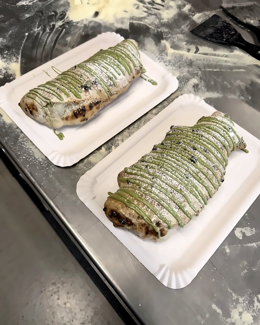 Süße Calzonen mit Pistaziencreme und Staubzucker auf Papptellern im Pizzakurs